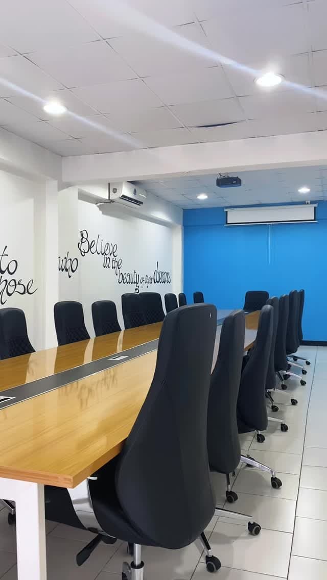 Boardroom with a long wooden table and black high-back chairs