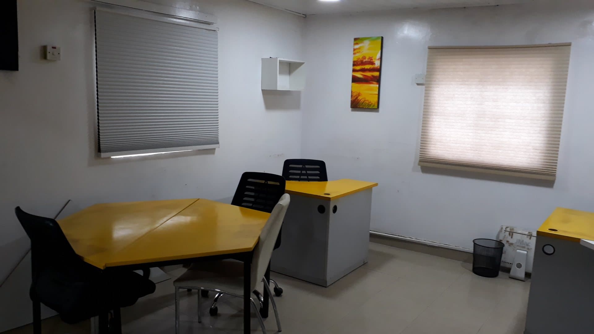 Small meeting office with a yellow table, office chairs and window blinds