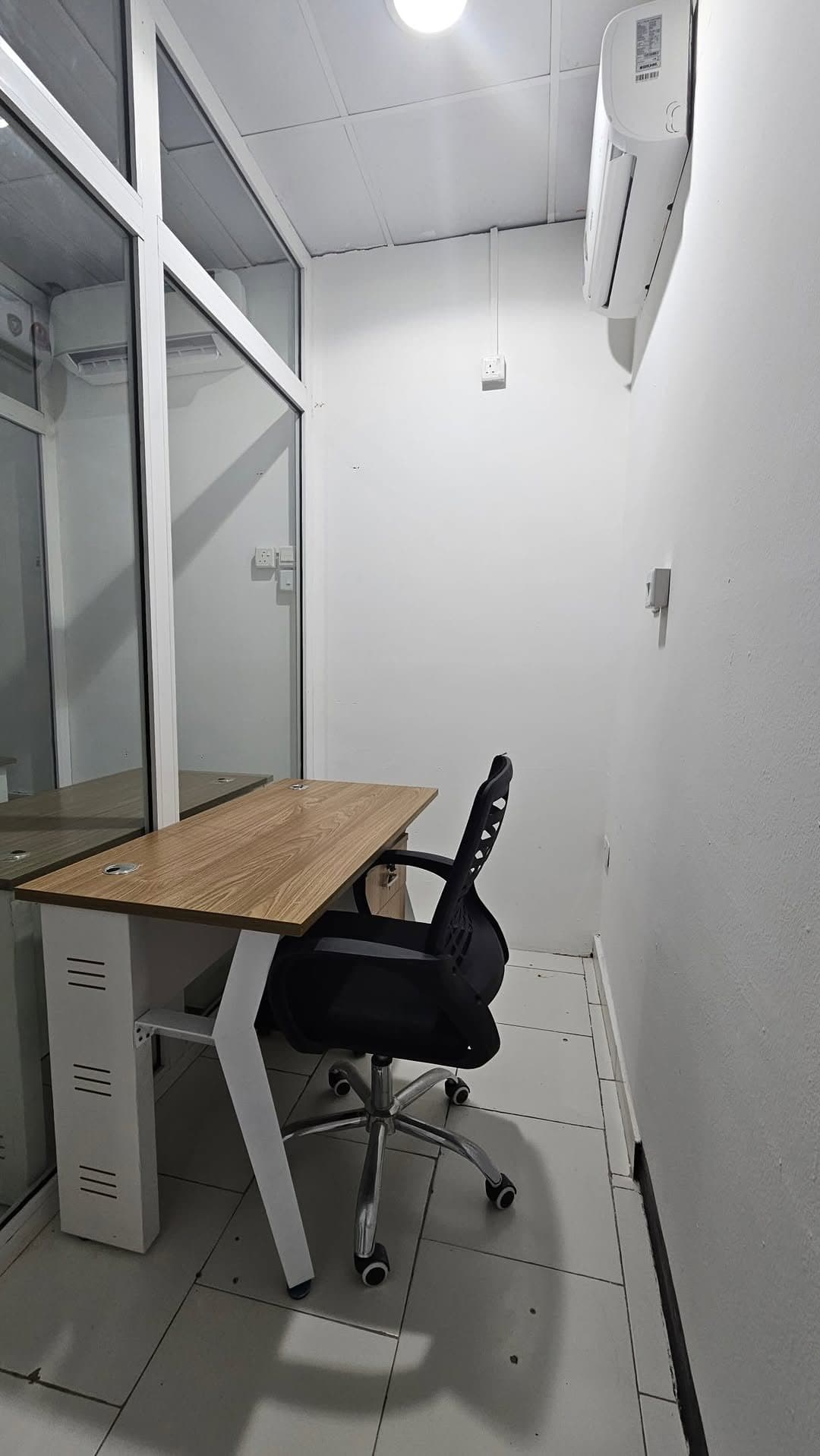 One-person private office with a wooden desk, mesh chair and glass door