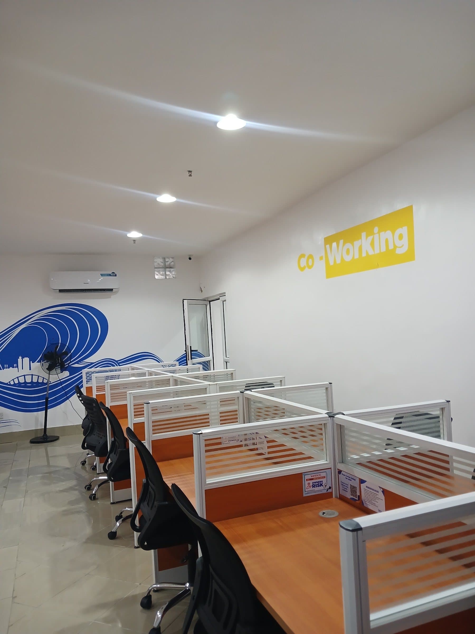 Row of screened workstations with orange desktops and ergonomic chairs